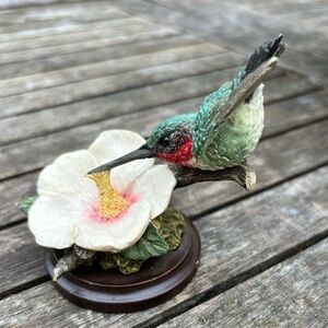 Country Artists ; Hummingbird on a Flower That sits on a wooden base.